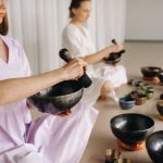 Two female yoga teachers play on Tibetan bowls in the gym during a yoga retreat